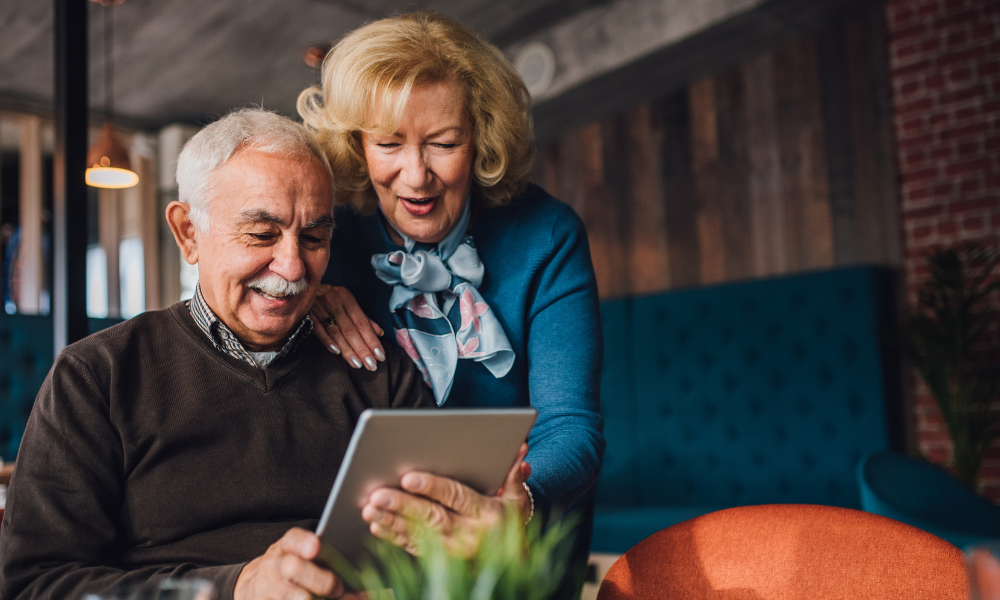 Older couple next to a couch looking at a tablet