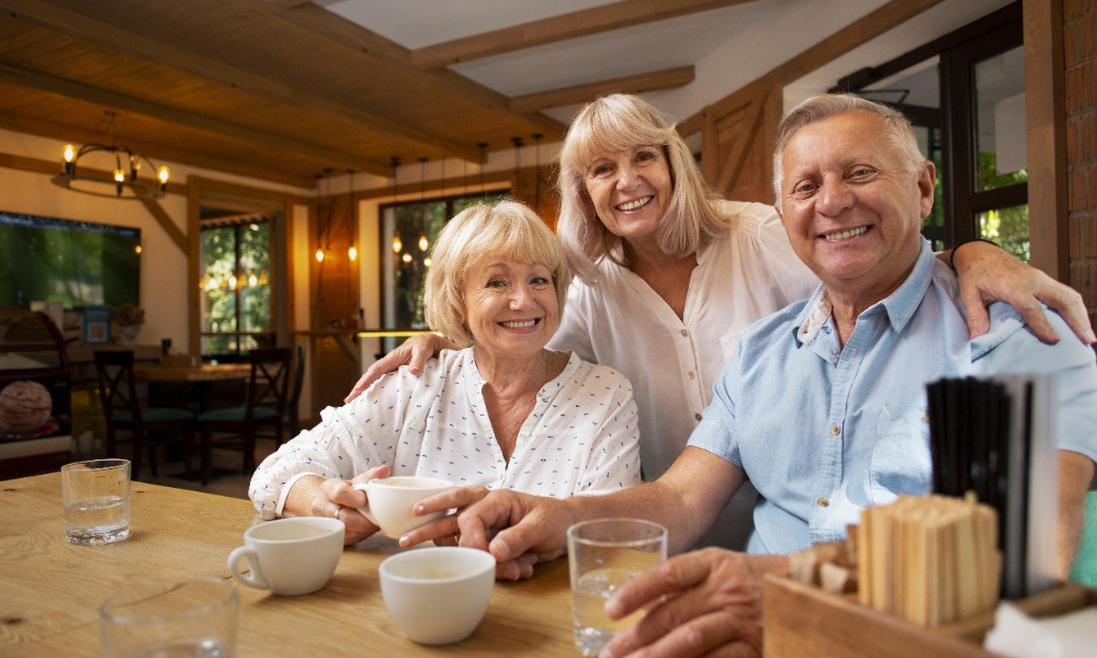 Three seniors smiling at the camera in a cafe